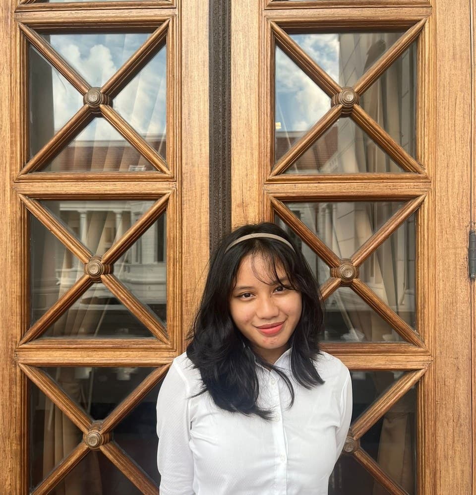 Noorliza Putri Yeo standing in front of carved wooden doors